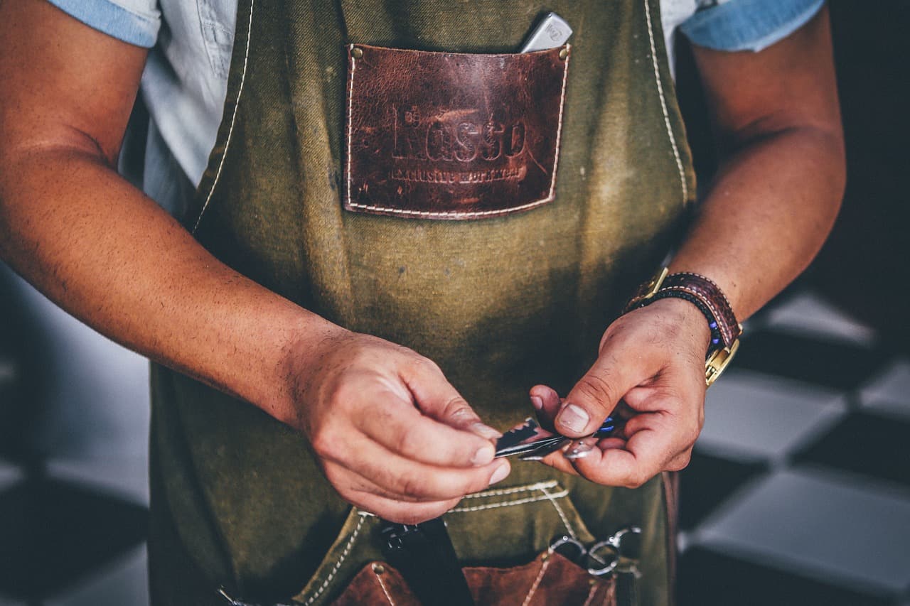 Barber in a leather apron getting his scissors ready
