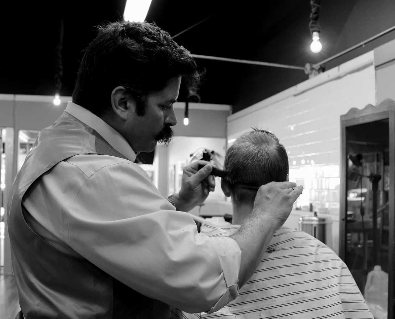 Barber trimming a customer's grey hair with comb and scissors