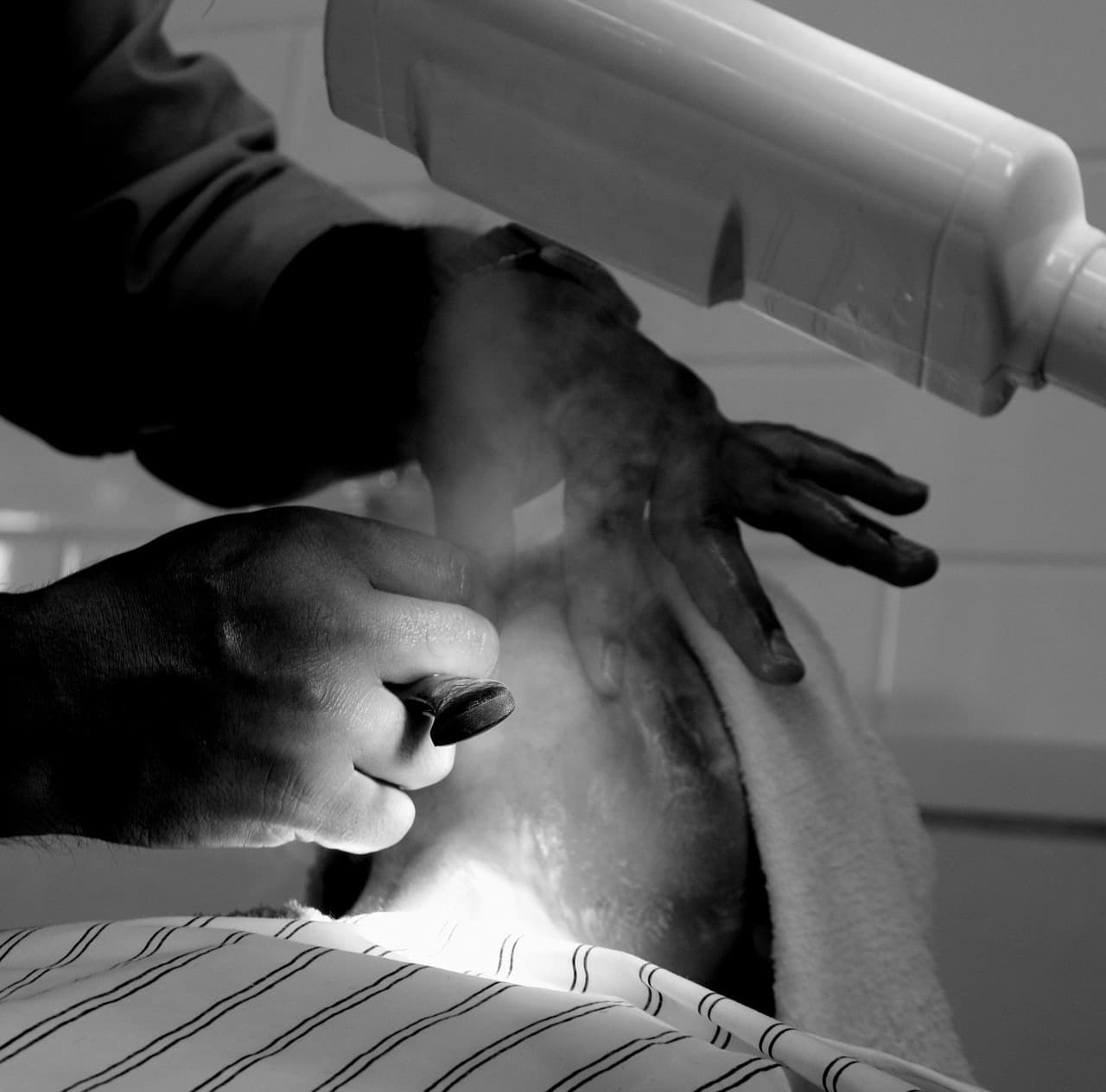 Straight razor shave with a towel around the customer, in black and white
