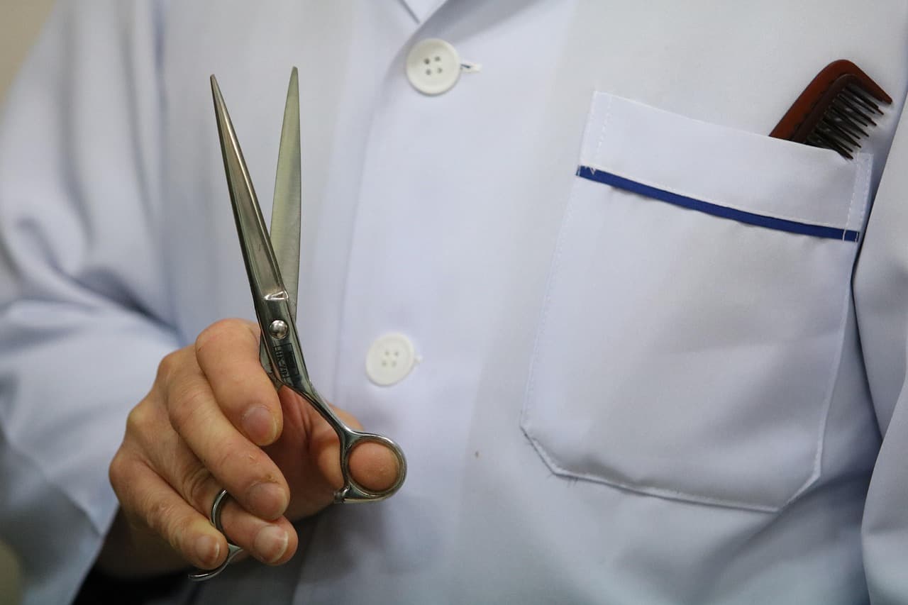 Barber in a white jacket holding a pair of scissors
